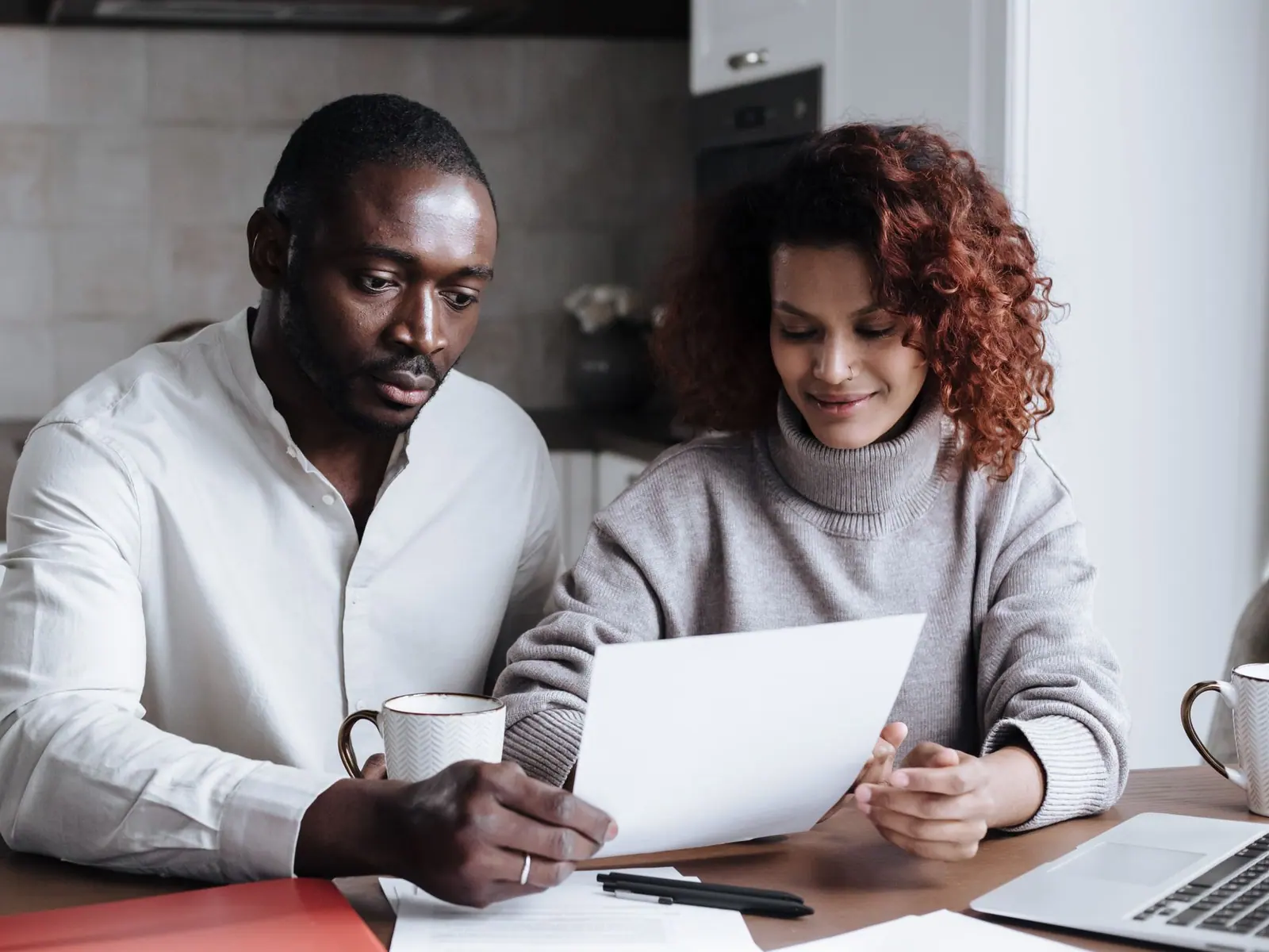 A couple reviewing household paperwork at their kitchen table