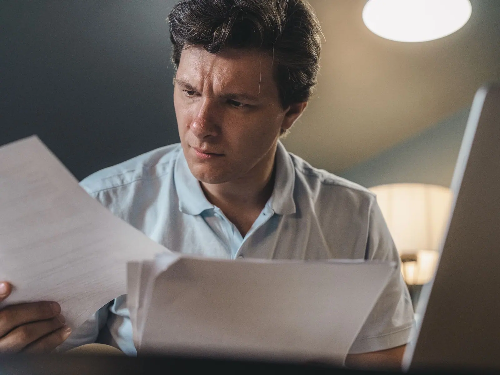 A person reviewing documents at a desk under a warm lamp