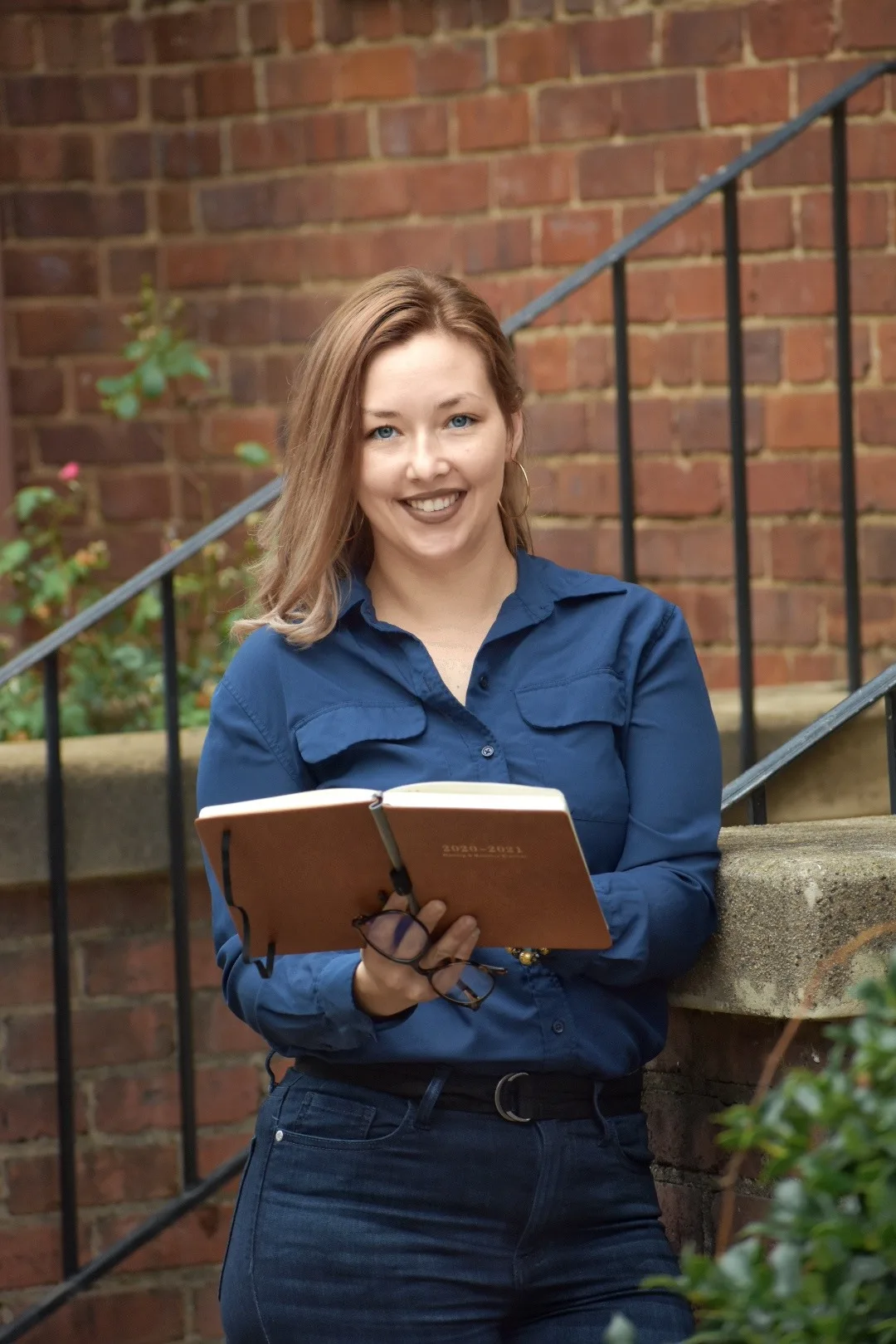 Thompson Bourque, founder of Crucial Business and Life Solutions, holding an open book on brick steps